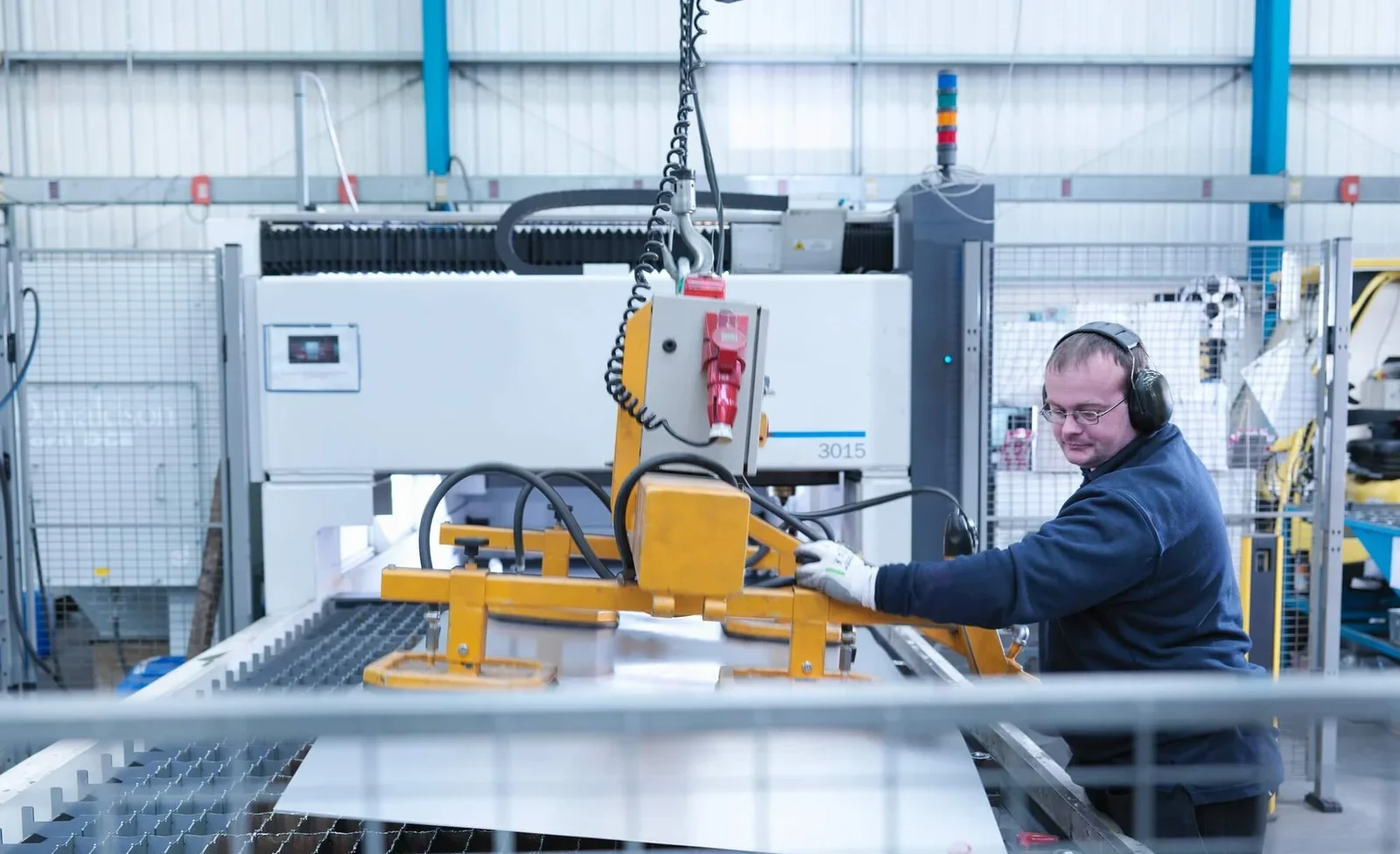 engineer loading sheet metal into laser cutter in engineering factory e1758251863588